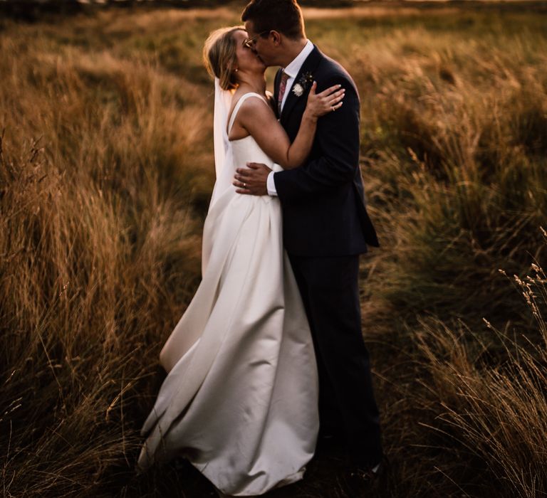 Bride and groom share a kiss at sunset