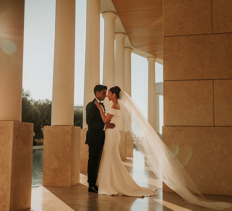 Bride & groom kiss under pillars on their wedding day | Hannah MacGregor Photo & Film