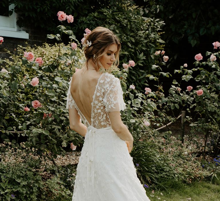 Bride with pinned up hair in a wrap wedding dress with lace overlay and low back detail by Constellation Ame 