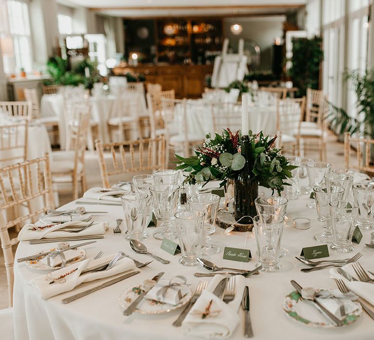 Floral bouquets sit in the middle of the table with white tablecloths and sage green accent colour