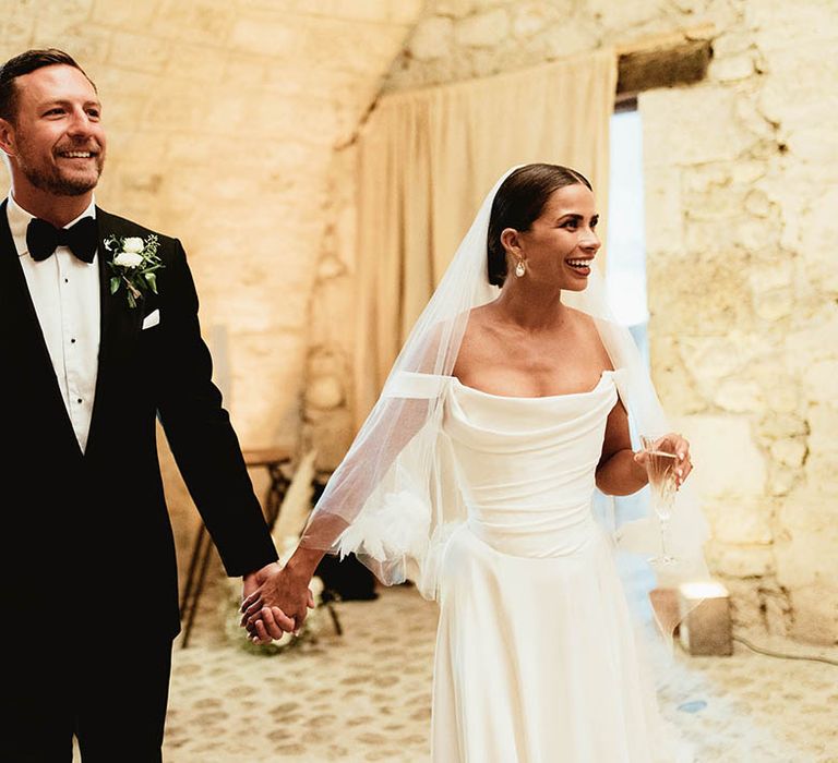 Bride & groom hold hands on their wedding day as they walk with one another