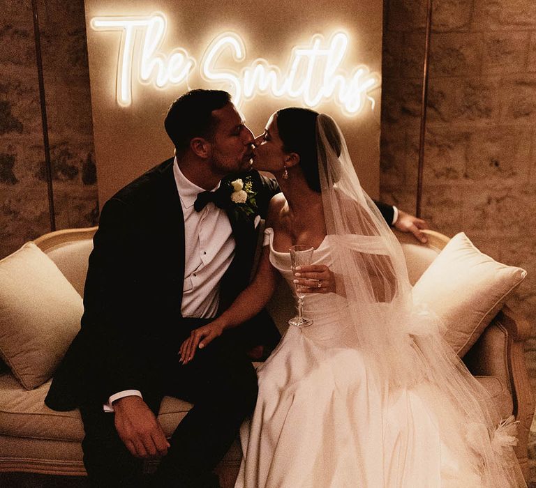 Bride & groom sit in front of personalised neon sign