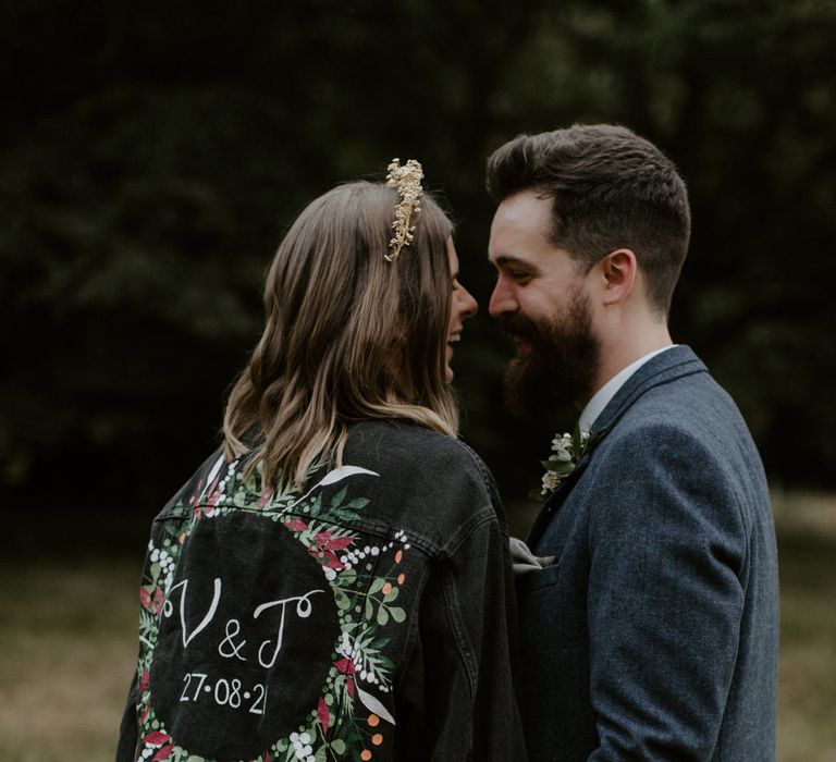 Bride kisses her groom whilst wearing personalised denim jacket for wedding day