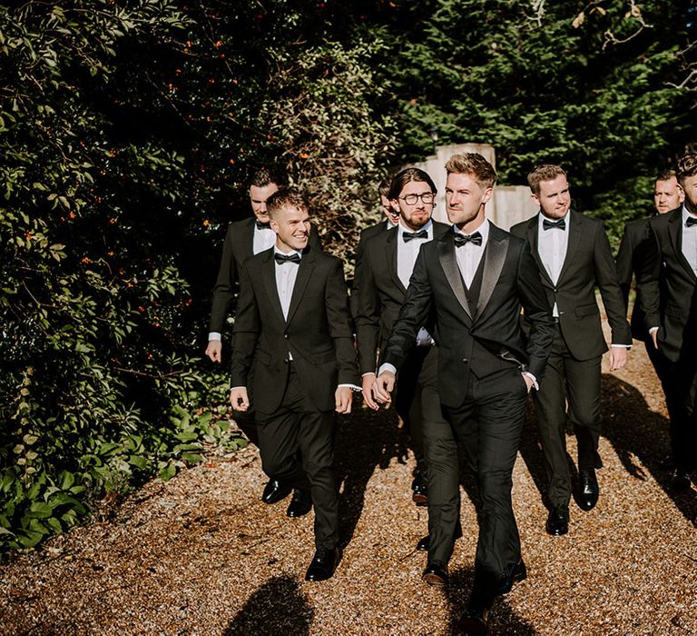 Stylish groomers in tuxedos and bow ties at elegant black tie wedding at Northbrook Park 