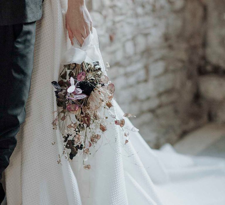 Bride in a princess wedding dress with waffle design holding a minimalist dried flower wedding bouquet 