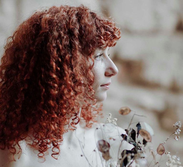 Bride with naturally curly red hair holding a dried flower wedding bouquet at Blackfriars Priory wedding inspiration 