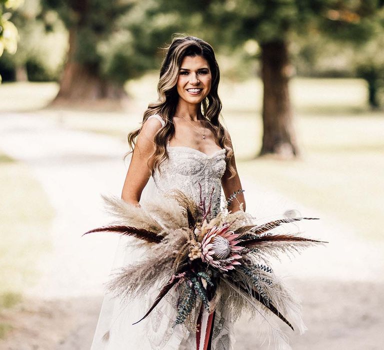 Bride holds floral bouquet outdoors 