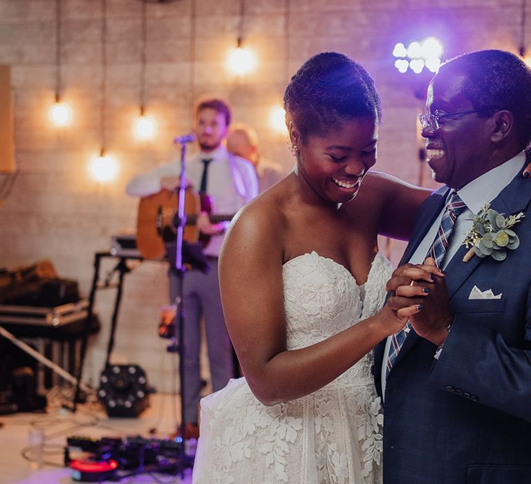 Bride in lace sweetheart wedding dress dances at reception while guitarist plays in the background