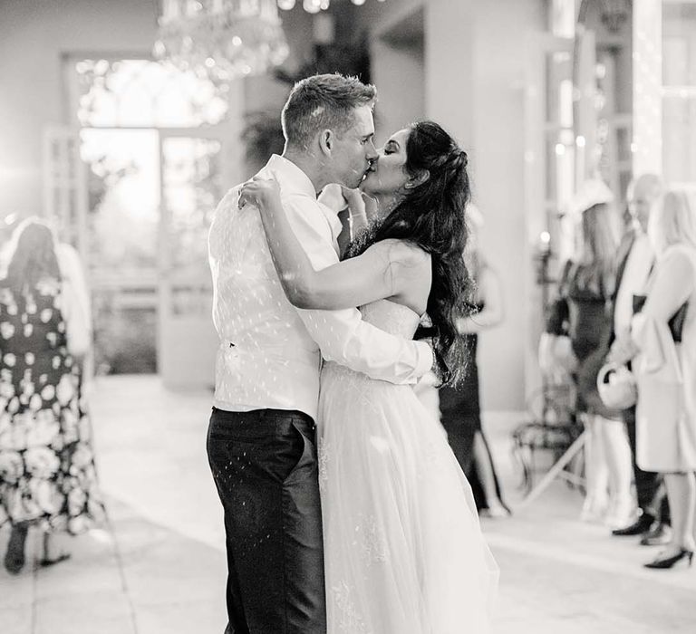 Bride & groom kiss in black & white image on their wedding day in The Orangery at Euridge Manor