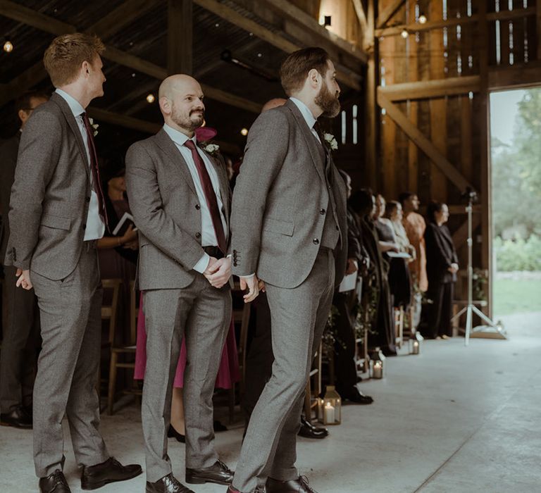 Groom awaits his bride at the end of aisle on his wedding day