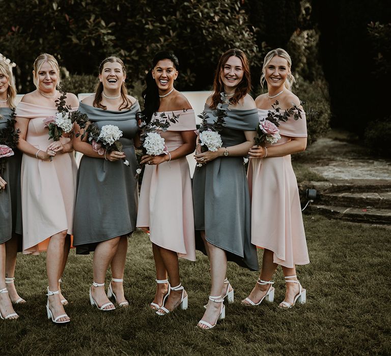 Bridesmaids wear tea length gowns complete in pastel pink and sage green