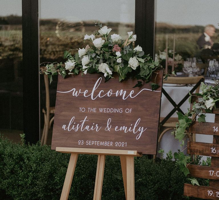 Dark wooden welcome wedding sign with white rose and greenery decor at Primrose Hill