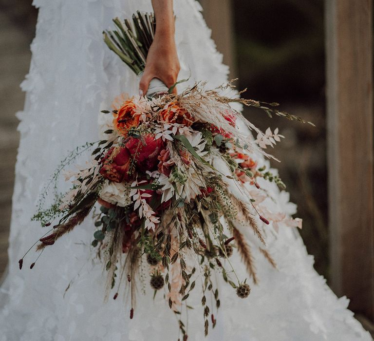 Bride's flower lace skirt wedding dress with large autumnal bouquet with orange and white flowers 