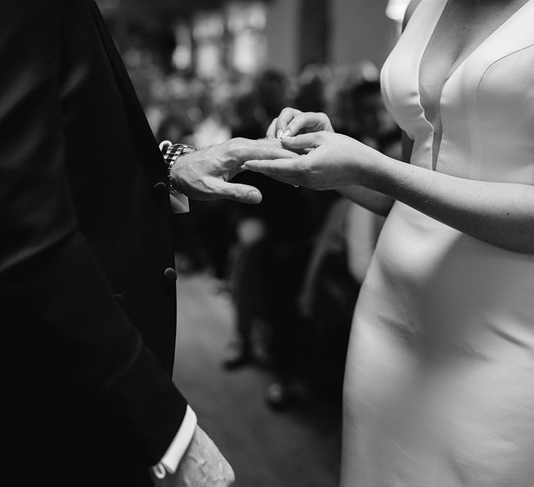 Bride in Made With Love wedding dress puts the ring on the groom's fingers 