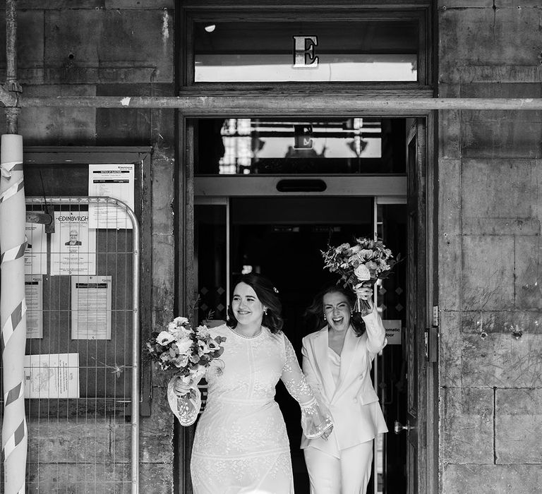 Brides celebrate as they leave wedding ceremony in black and white image