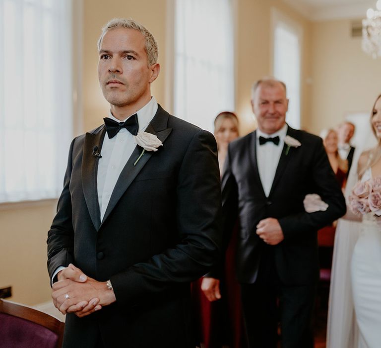 Father of the bride walks the bride in Made With Love wedding dress down the aisle carrying a pink rose round bouquet 