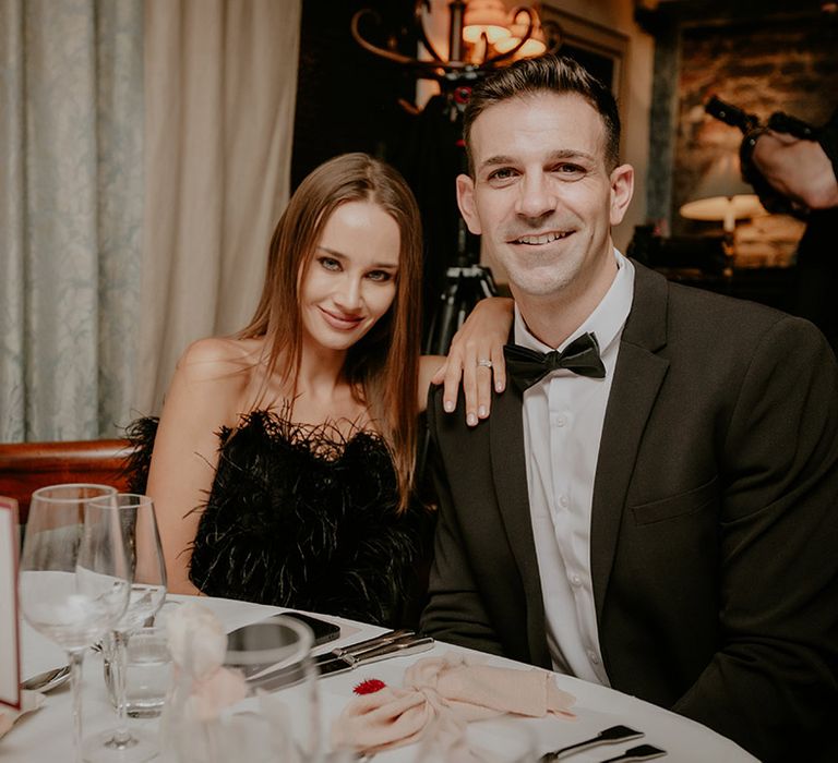 Wedding guest in black feather outfit and guest in black tie 