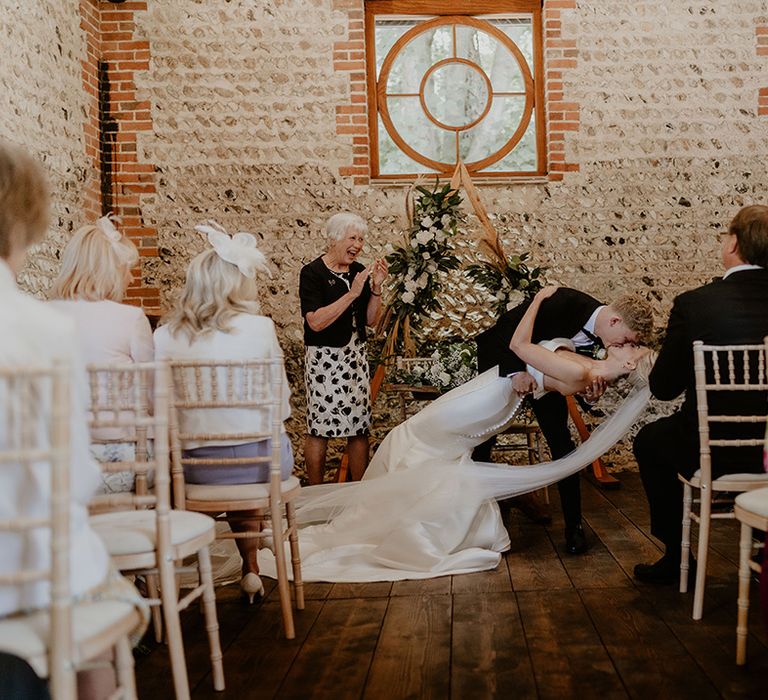 Groom in black tie dips the bride in a strapless gown low for their first kiss as husband and wife 