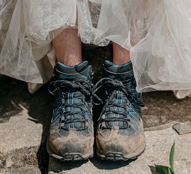 Bride wears hiking boots beneath wedding dress to walk through grounds of Neidpath Castle for couples portraits