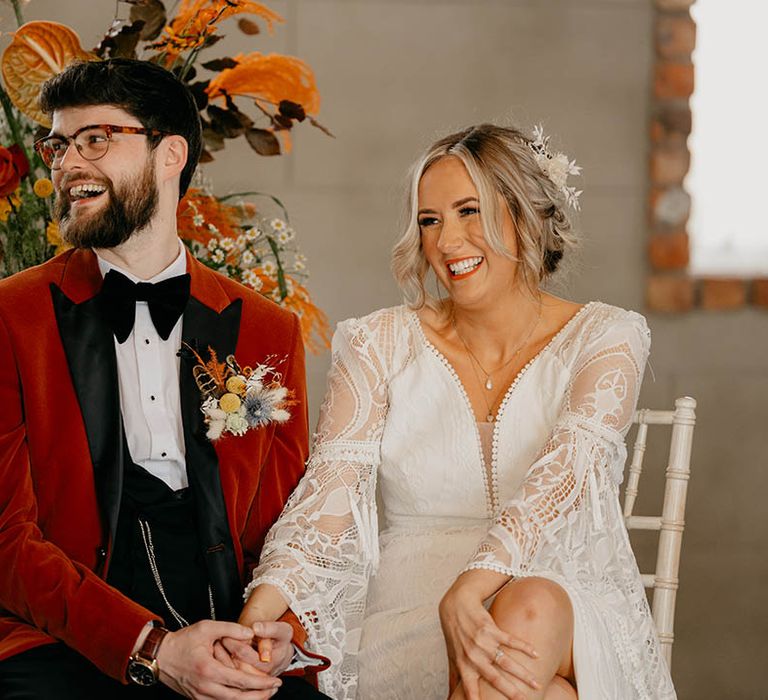 Bride and groom laugh holding hands during their wedding ceremony 