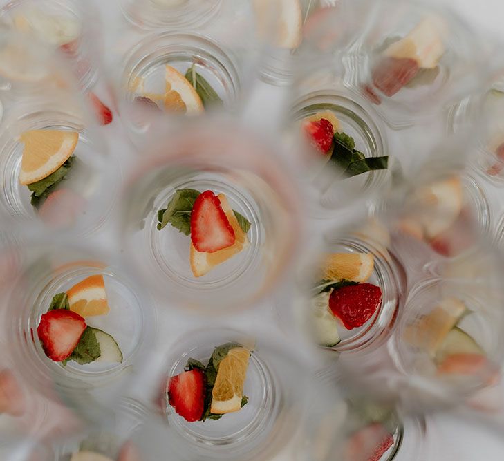 Strawberries, orange and mint in glasses on white tablecloth 