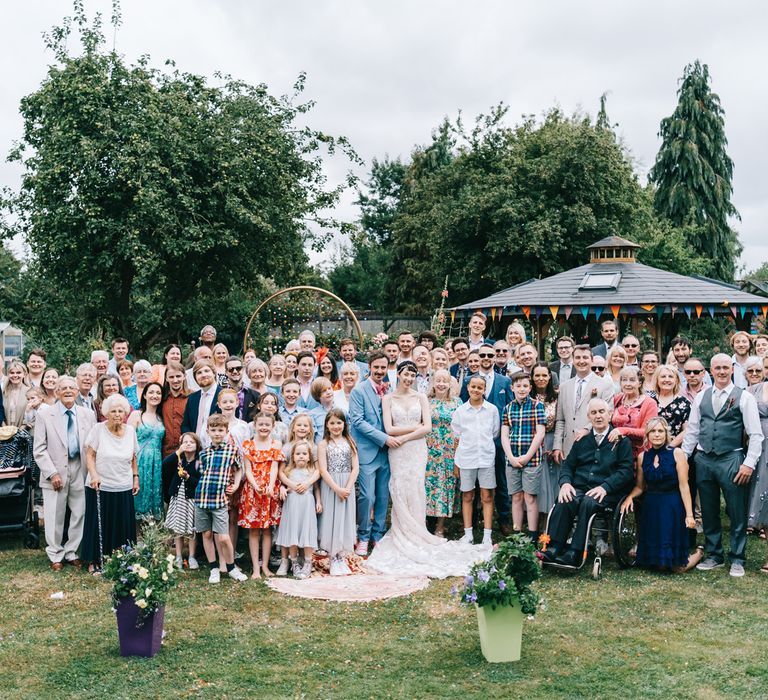 Wedding party gather outdoors for back garden wedding photo