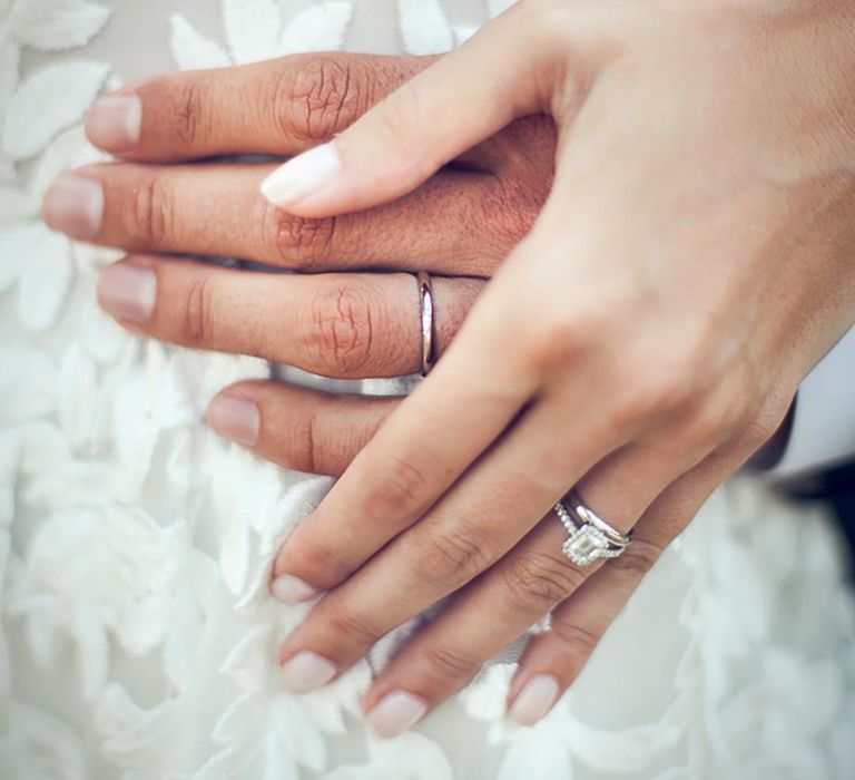 Bride wears a sparkly pave engagement ring and plain silver wedding band with the groom wearing a plain band 