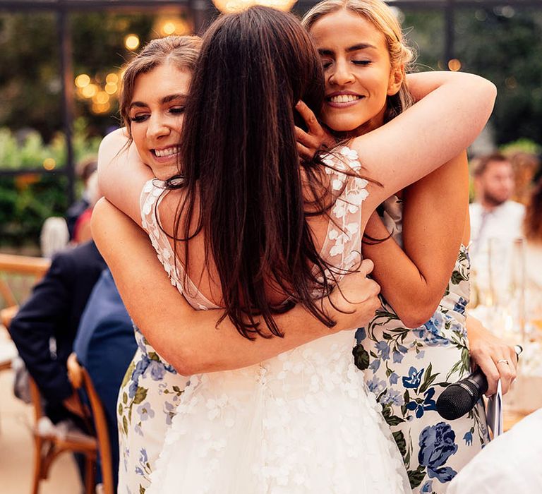 Bride in floral appliqué wedding dress from Phillipa Lepley hugging her bridesmaids in blue floral dresses