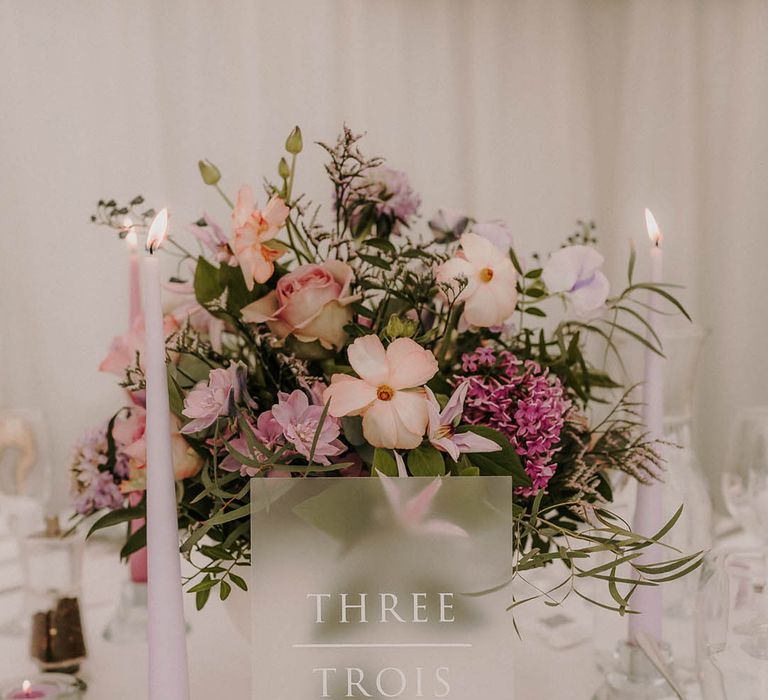 Lilac and purple wedding flower centrepiece arrangement with purple taper candles and tea lights 