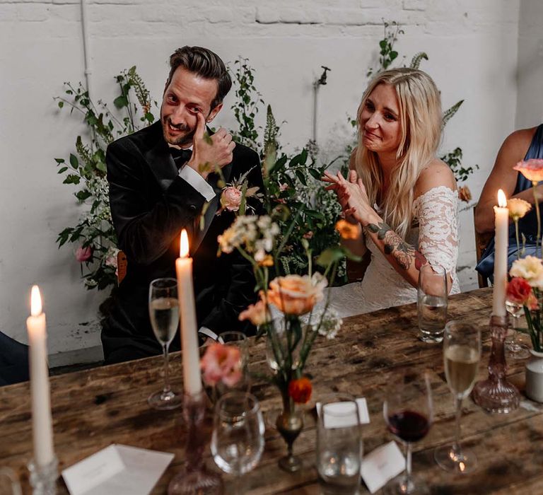 Bride in boho two piece lace bridal outfit and groom in dark tux with bowtie at modern stylish wedding reception