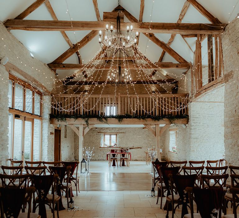 Kingscote Barn rustic wedding barn venue decorated with fairy lights, with burgundy chair back decor with candle decor