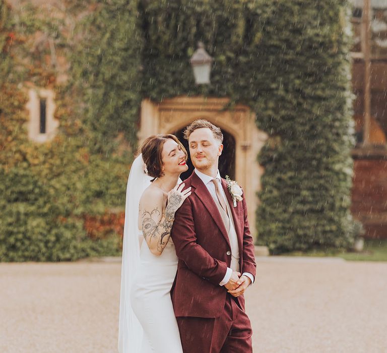 Bride & groom stand in the rain outdoors on their wedding day at St Audries Park