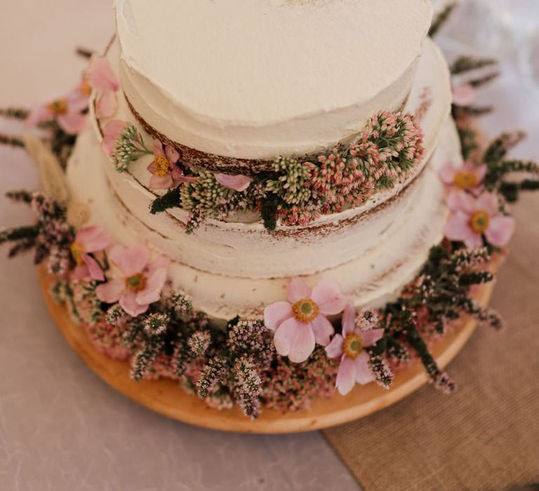 Two tier wedding cake with frosting and pink flowers 