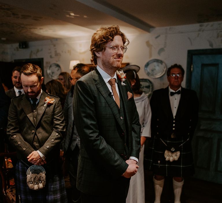 Groom wearing dark suit with orange tie and autumnal boutonniere waiting for bride at the alter of The Zetter Townhouse 