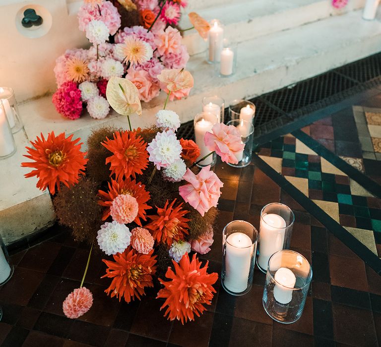 Colourful cascading florals complete with peonies and anthurium alongside white pillar candles 