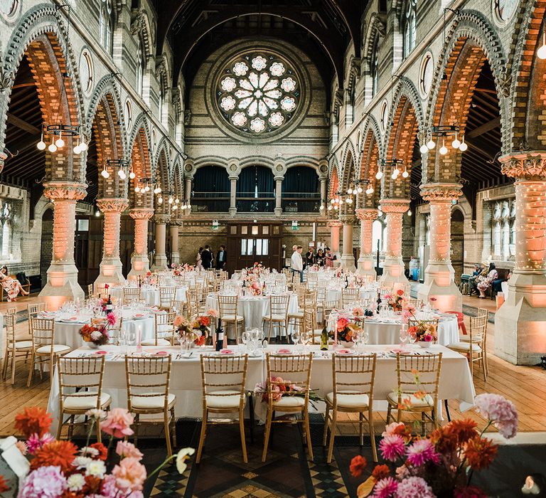 Colourful floral bouquets line wedding tables covered in white tablecloths alongside pink Chinese inspired name cards 