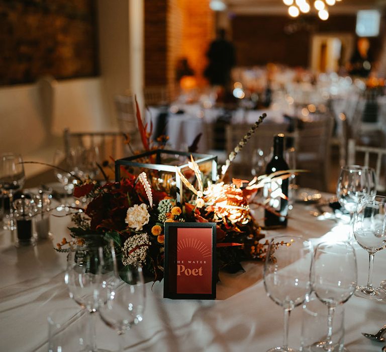 Retro styled table name stationery beside Autumnal floral arrangements 