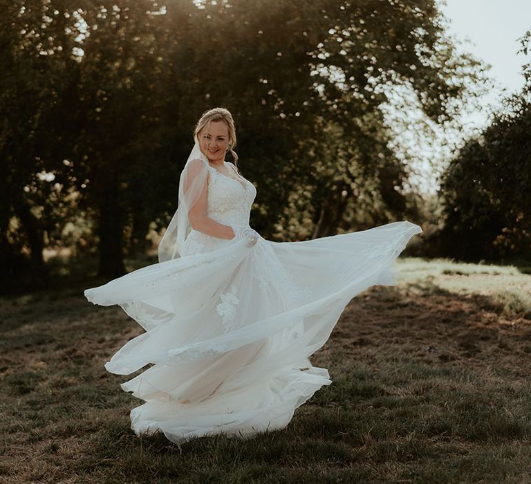 Bride twirls around in lace wedding dress during outdoor portraits 