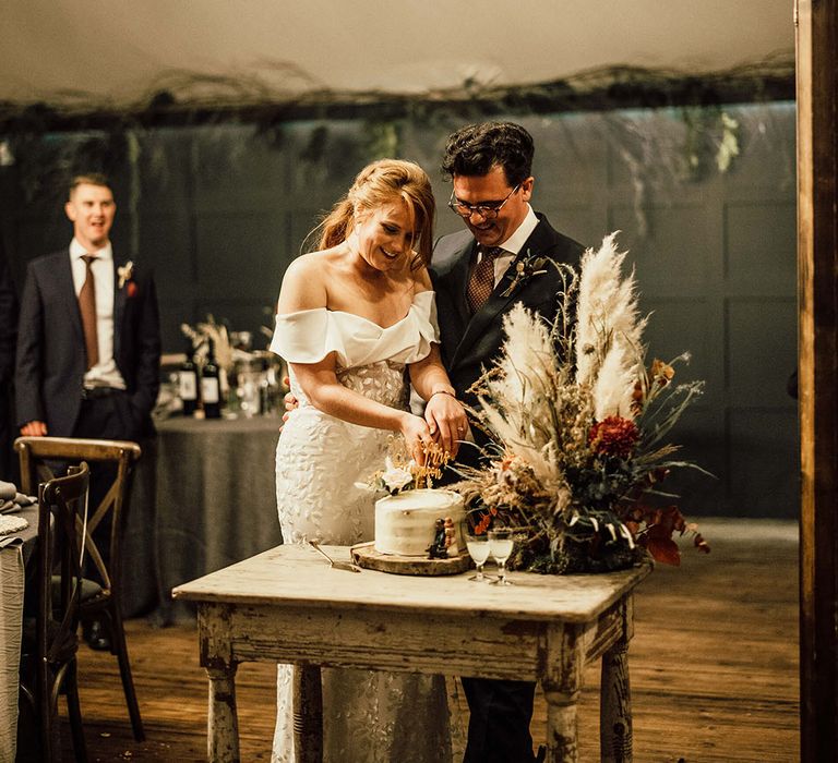 Bride & groom cut naked wedding cake with DIY cake topper 