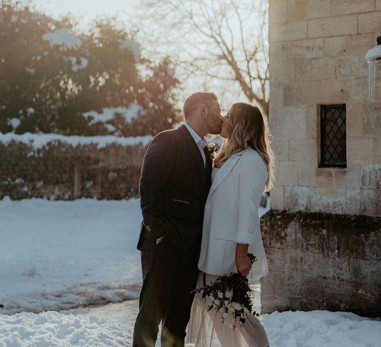 The sun illuminates the bride in a ruffle wedding dress and white blazer with the groom in a checkered suit for Stroud Registry Office wedding 