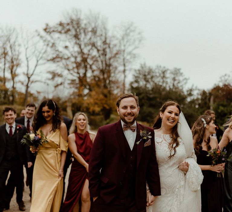 The wedding party in mismatched bridesmaid dresses and mismatched suits for a boho eclectic autumnal wedding day 