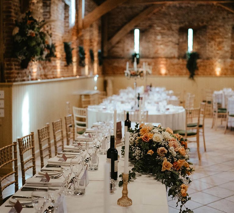 Rustic Elms Barn wedding with the tables decorated in a dusky pink with peach and orange flowers and gold candle holders with white candles in 