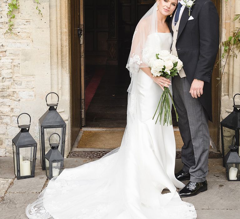 Bride in mermaid wedding dress in sleek material with the groom in morning suit for country house wedding 