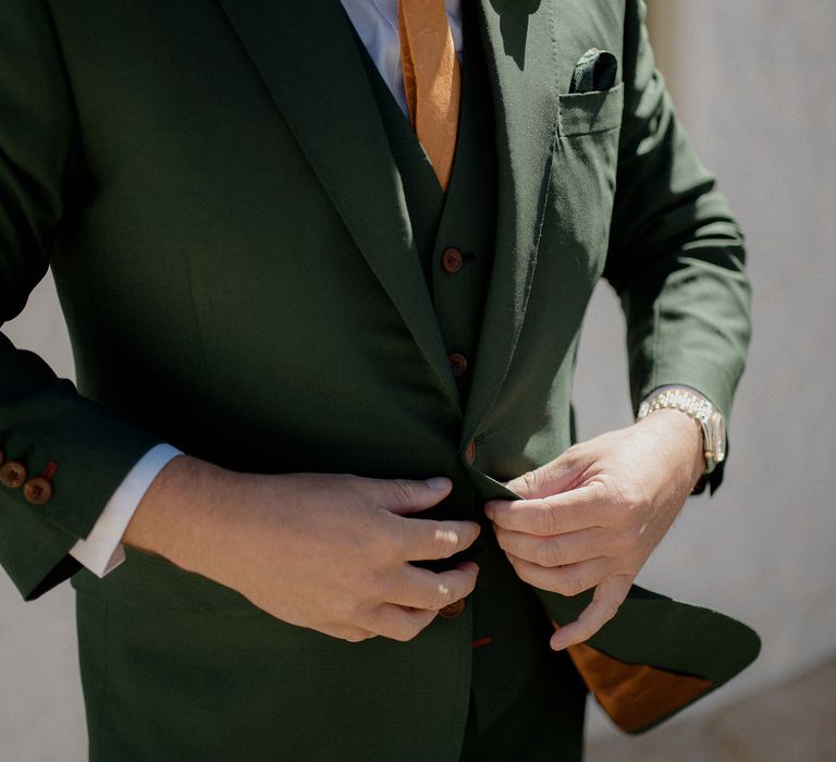 Dark green groom's suit with orange tie at destination wedding 