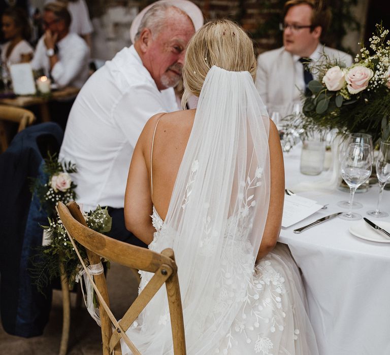 The bride sitting down with a floral embroidered wedding veil to match the floral wedding dress 