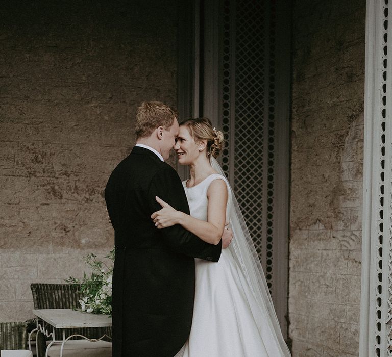 The bride wearing a high neck San Patrick wedding dress embracing the groom at their traditional and intimate wedding 