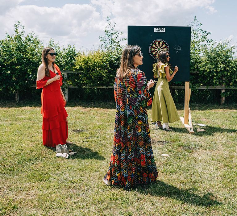 The wedding guests play darts outside for wedding games entertainment 