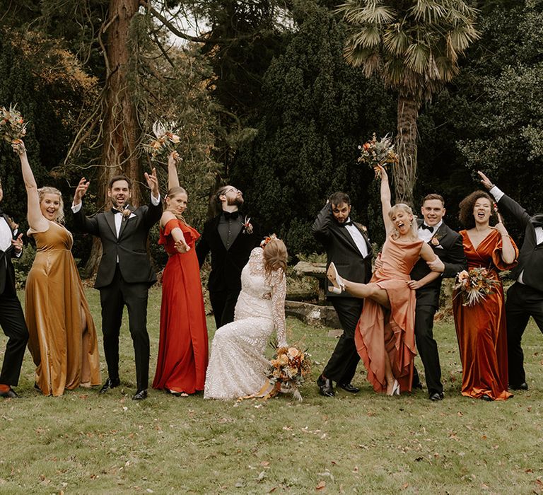 A black tie wedding with the groomsmen and groom in black tie with the bridesmaids in autumnal bridesmaid dresses and the bride in a boho lace wedding dress 