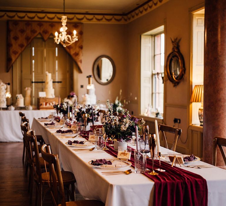 Winter wedding with dark red wedding tablescape with gold rimmed glasses and charger plates 