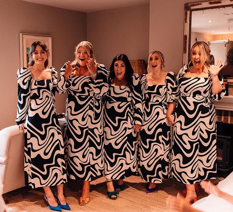 Black and white monochrome patterned bridesmaid dresses with a square neckline and puff sleeves wearing colourful shoes 